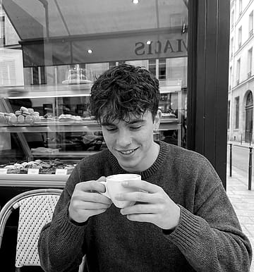 Thiago con un pocillo de café entre las manos, en la vereda de un café.