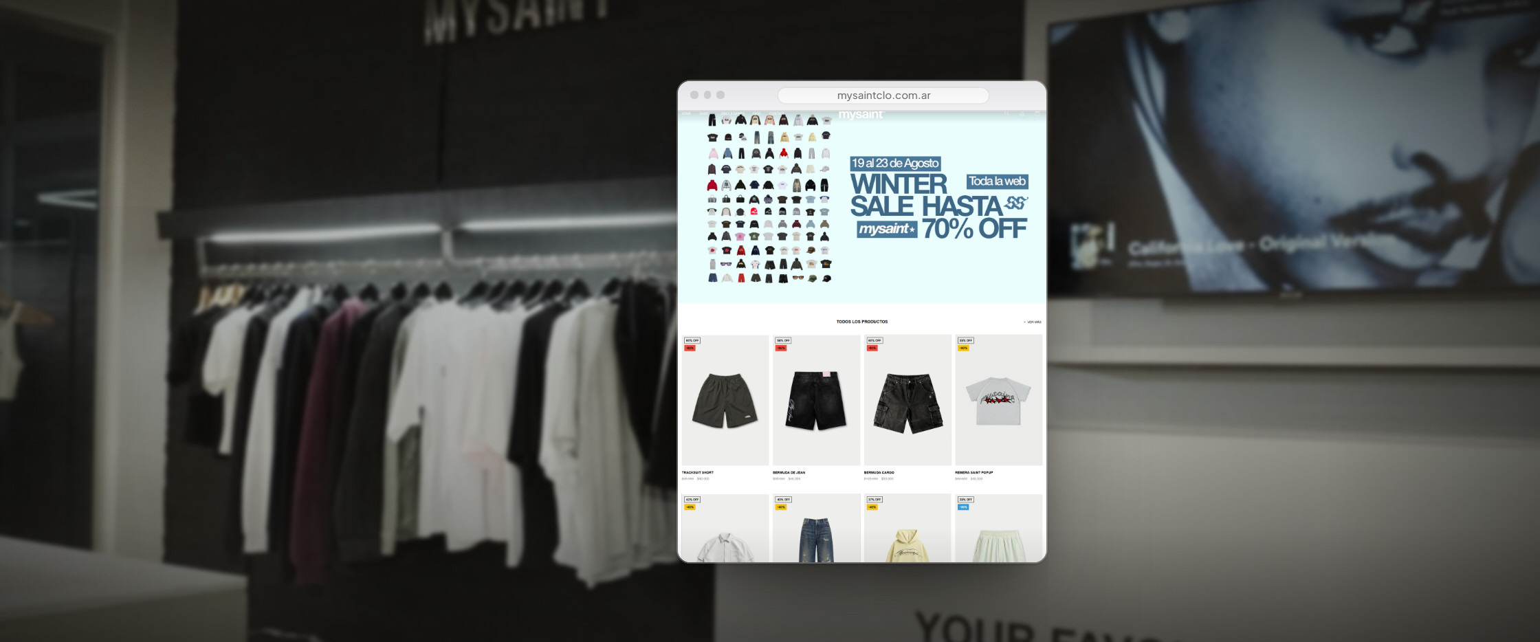 La tienda abierta en un navegador, flotando sobre la foto del local: una percha larga de remeras y buzos iluminada contra la pared negra, el cartel de la marca arriba y el mostrador al fondo. En pantalla, la portada de la tienda: el banner de la campaña de temporada con descuentos de hasta 70 % y, debajo, la grilla de productos con su foto, su chapa de descuento y el precio anterior tachado junto al precio final.